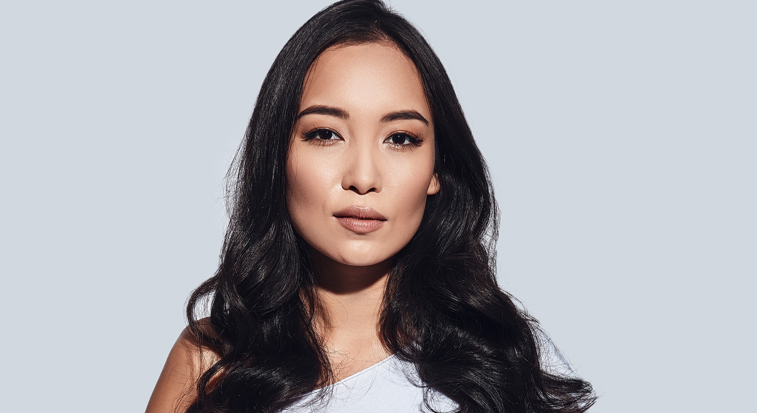 Woman with long dark hair, neutral expression.