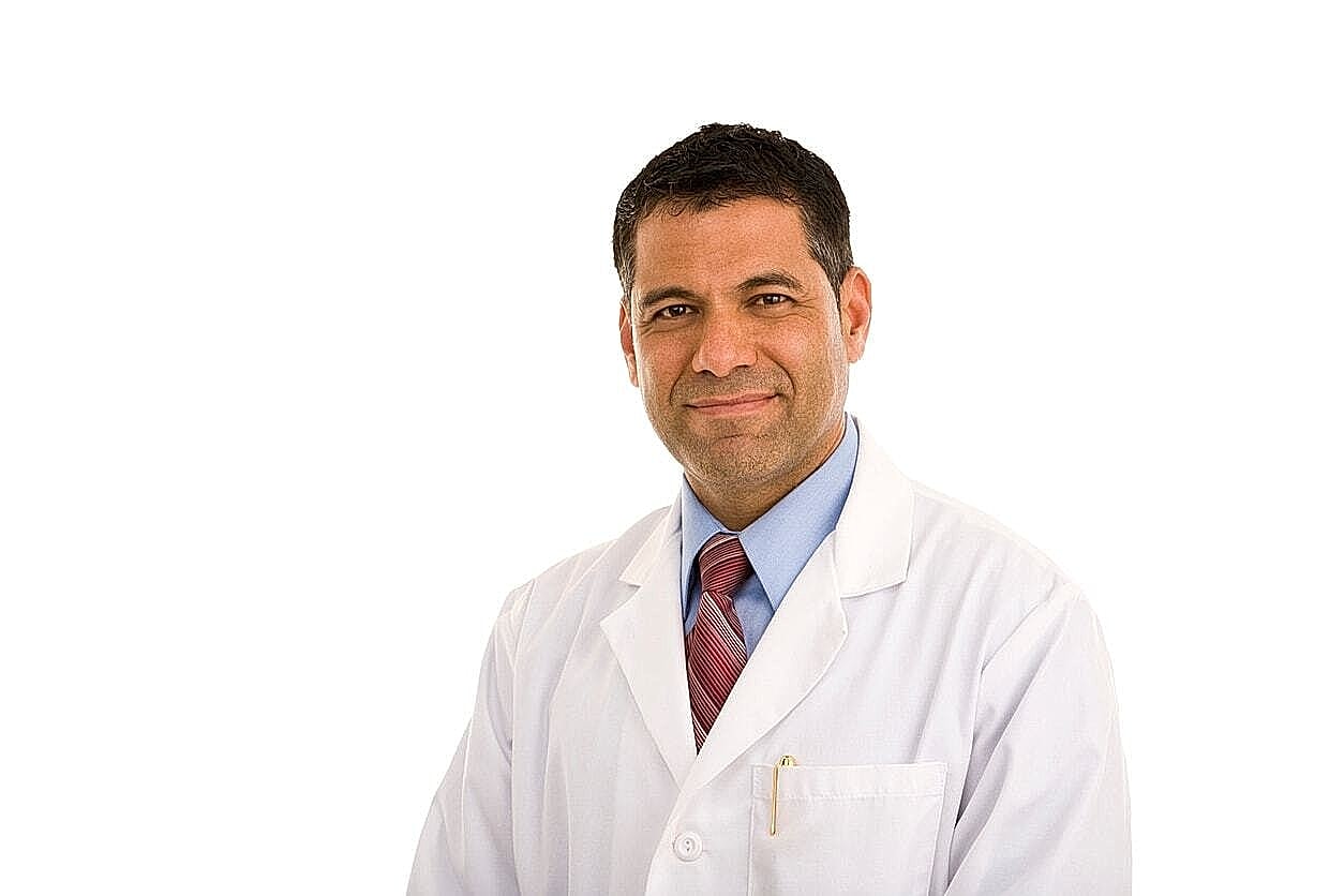 Smiling doctor in white coat against white background.