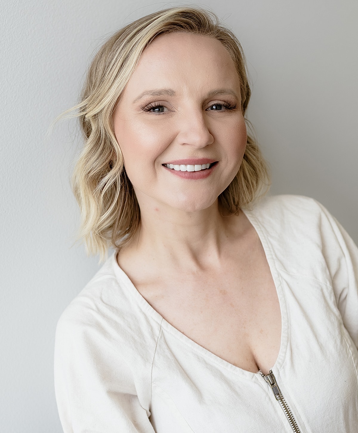 Woman smiling with hand on chin, wearing black.