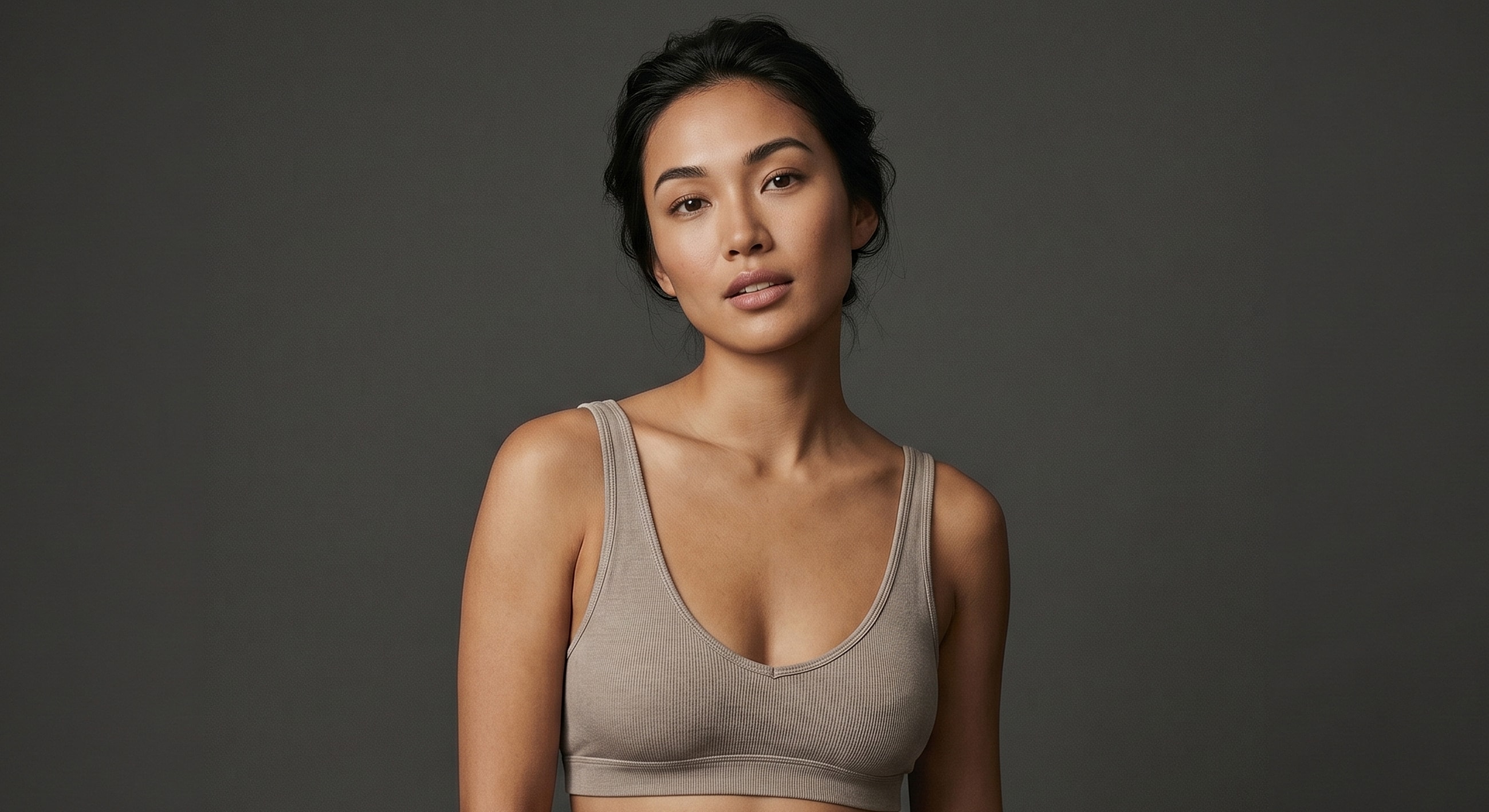 Model wearing a beige cropped top against gray background.