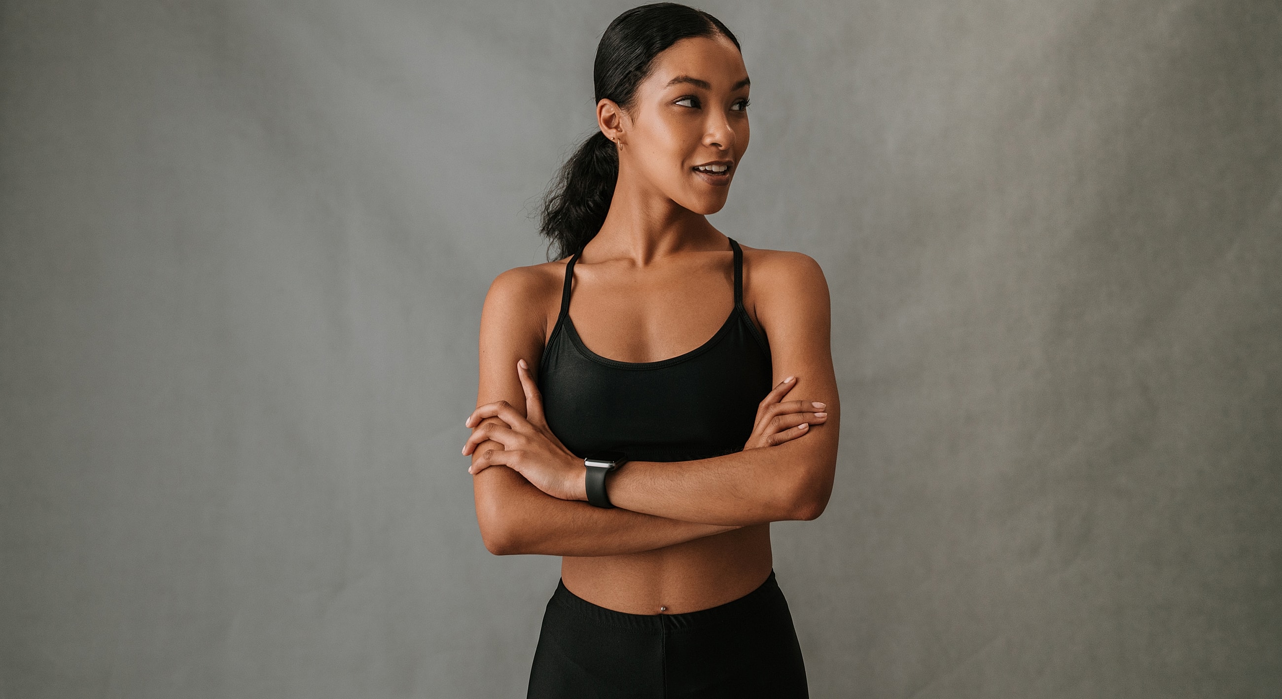 Confident woman in black athletic wear, arms crossed.