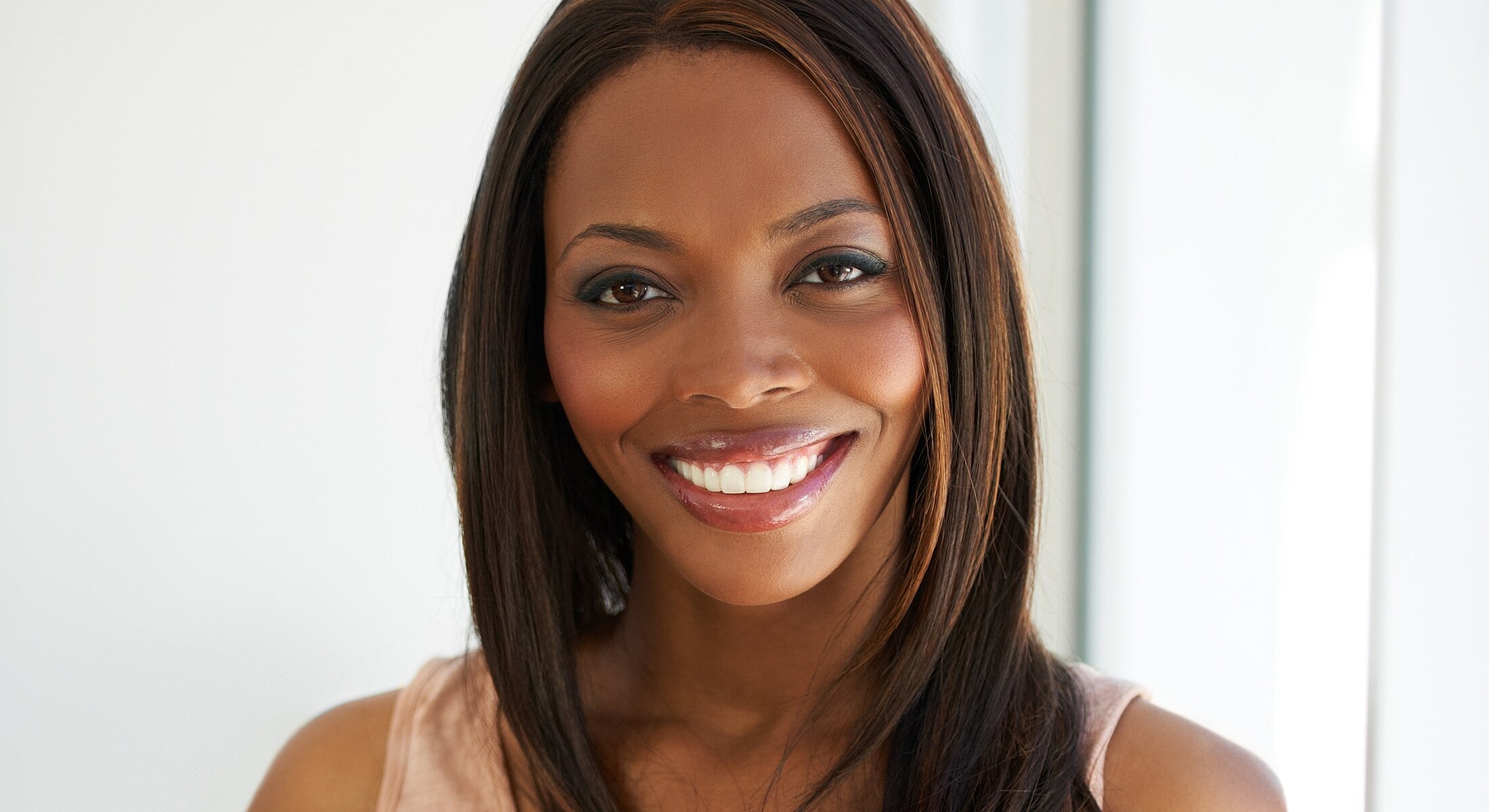 Smiling woman with long hair and natural makeup.