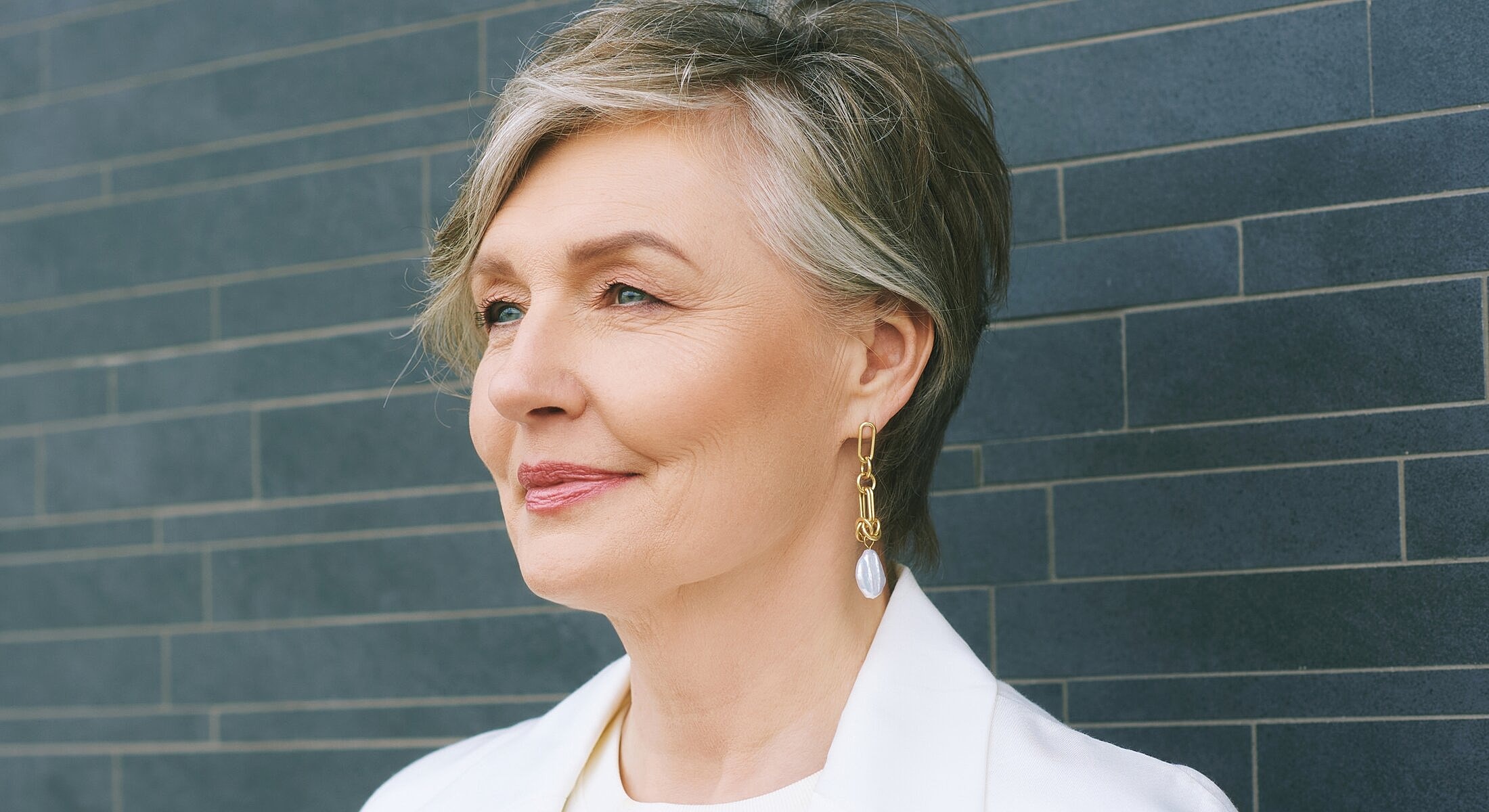 Smiling mature woman with elegant hairstyle and earrings.