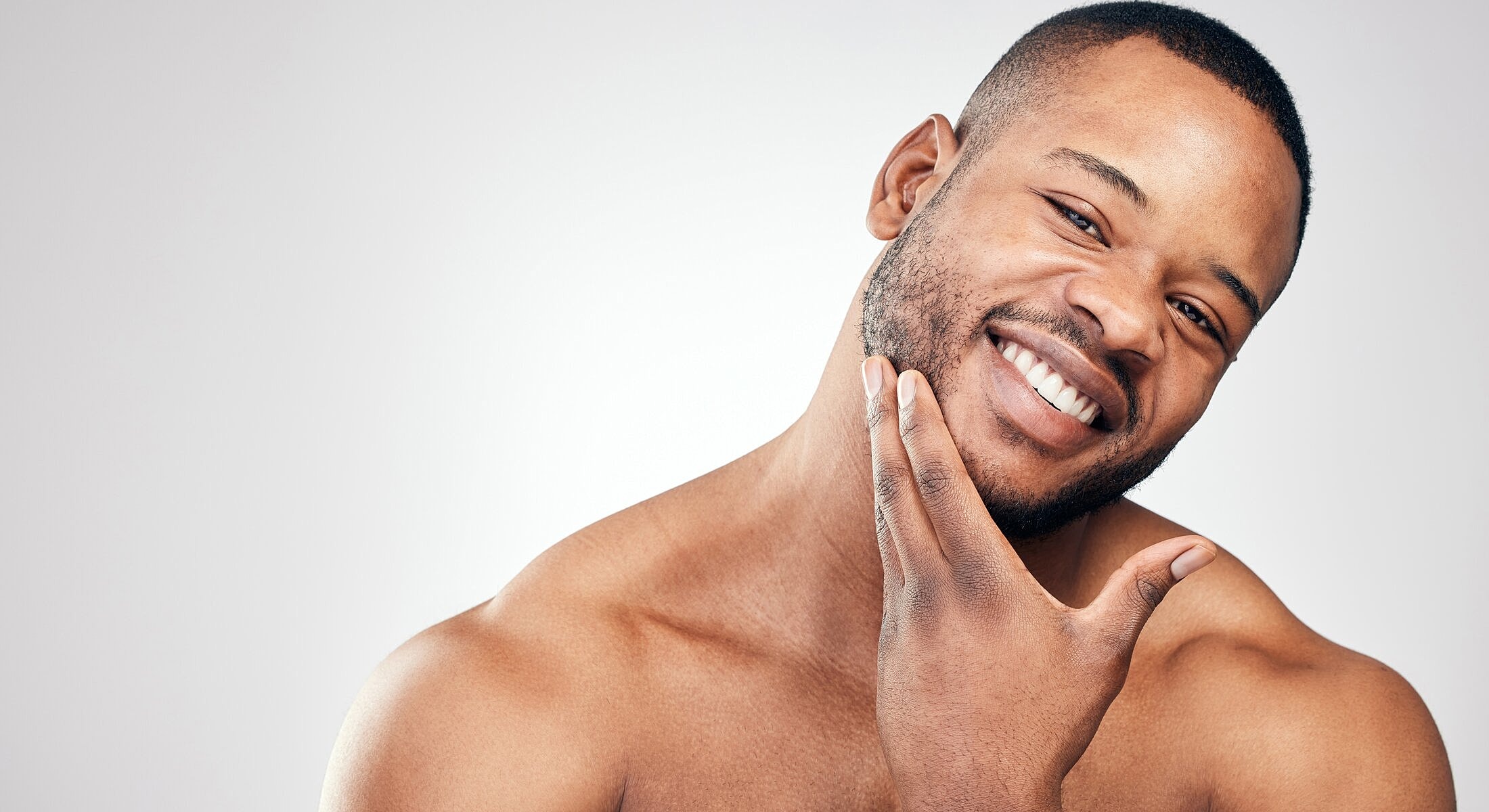 Smiling man touching his chin confidently.