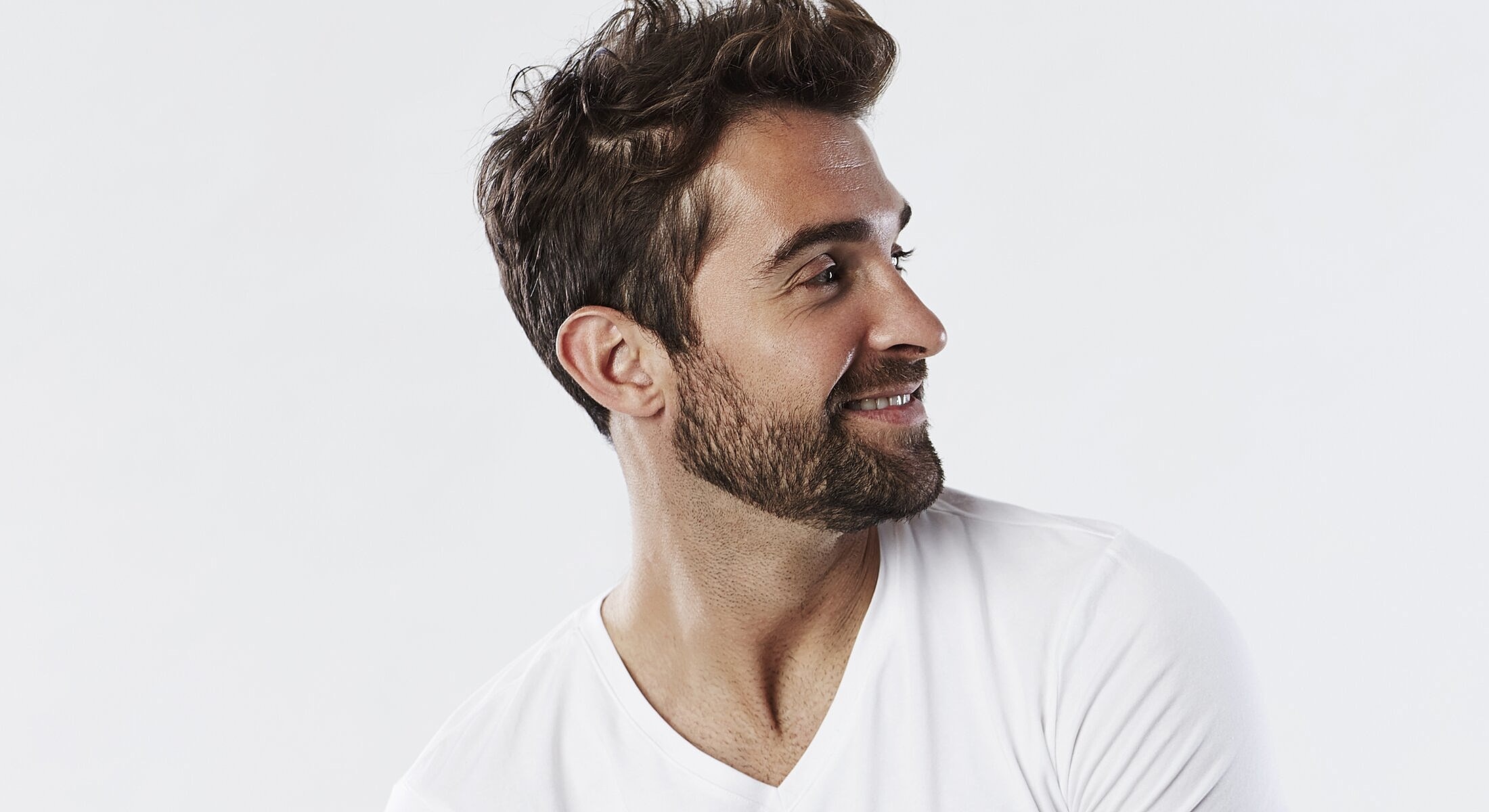 Smiling man in a white T-shirt, profile view.