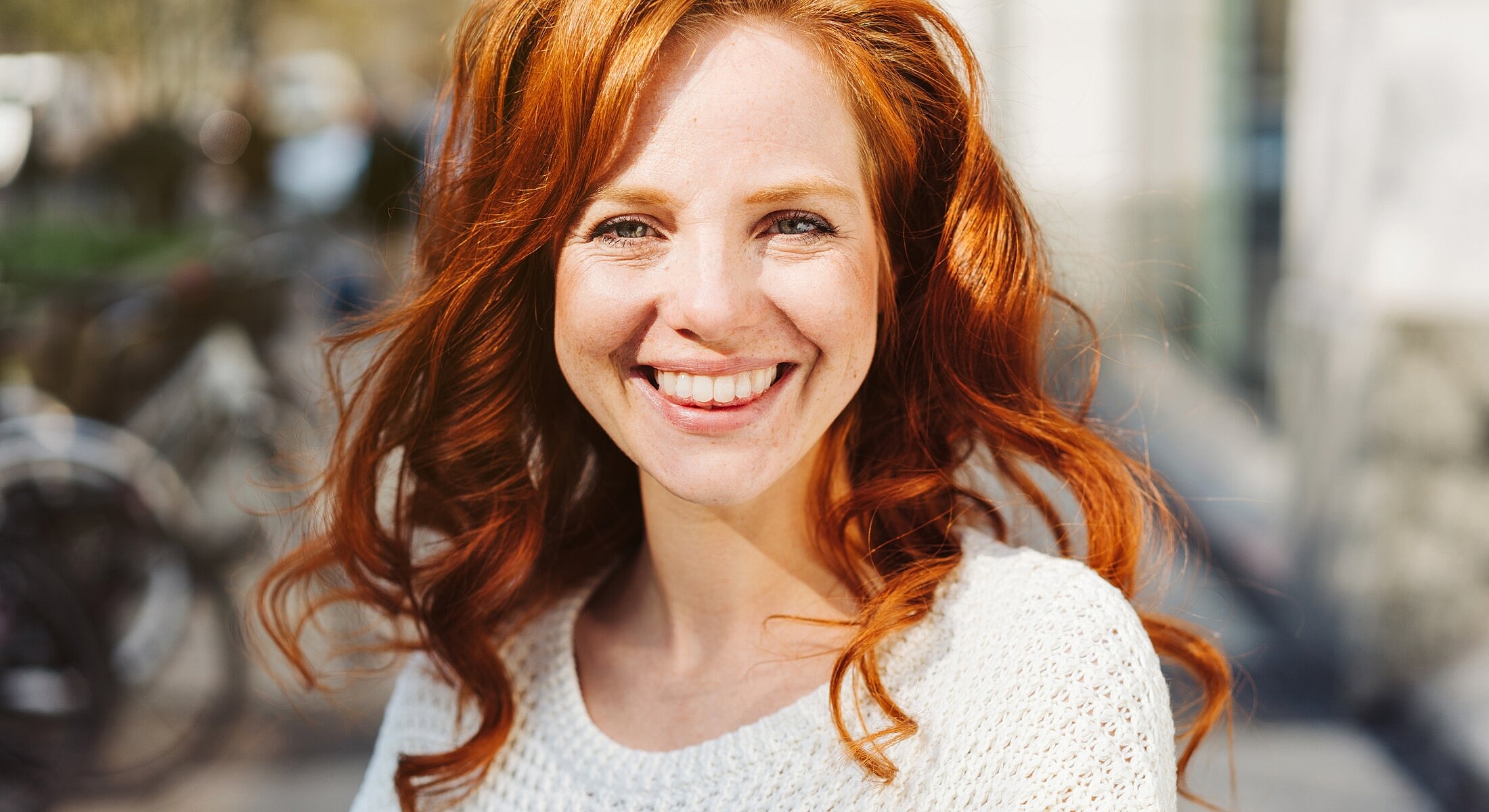 Smiling woman with long wavy red hair.