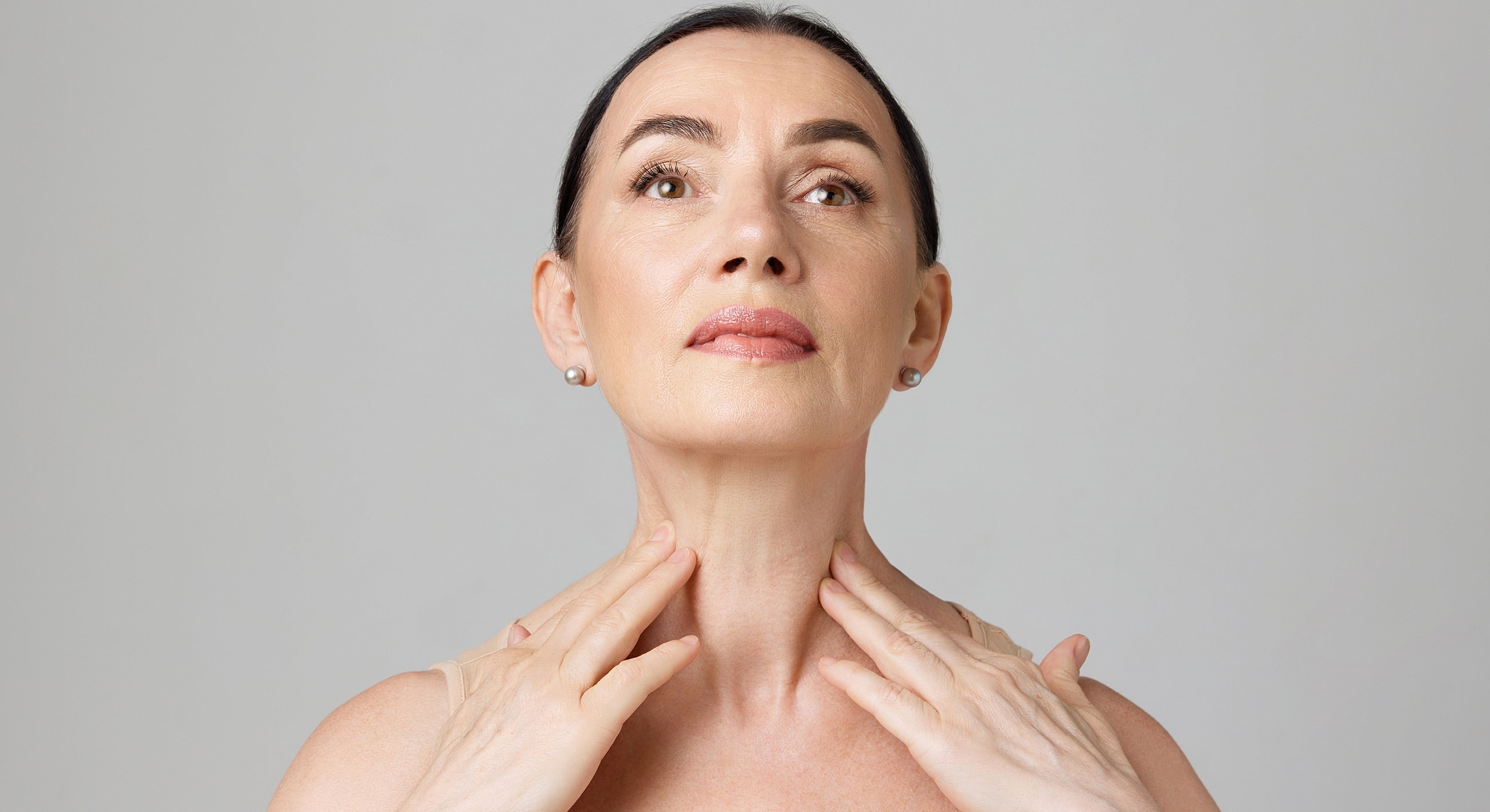 Woman applying skincare to her neck.