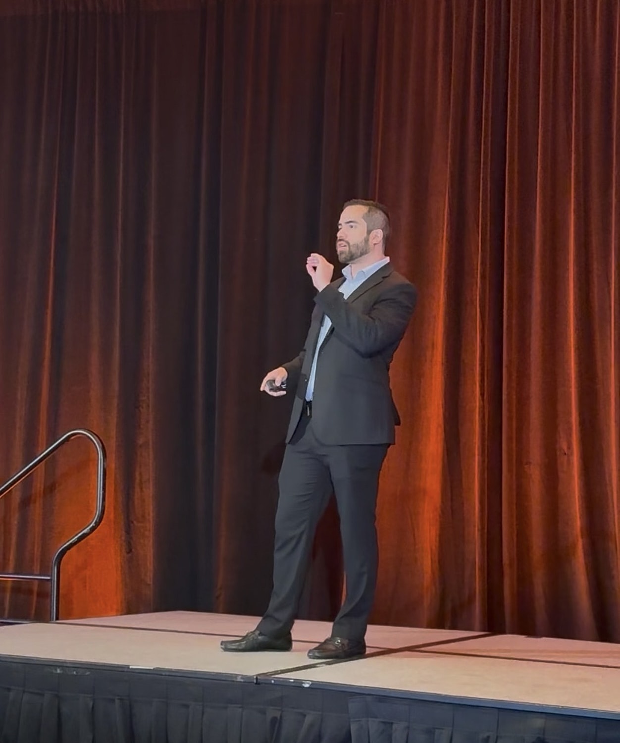 Speaker presenting on stage at a conference.