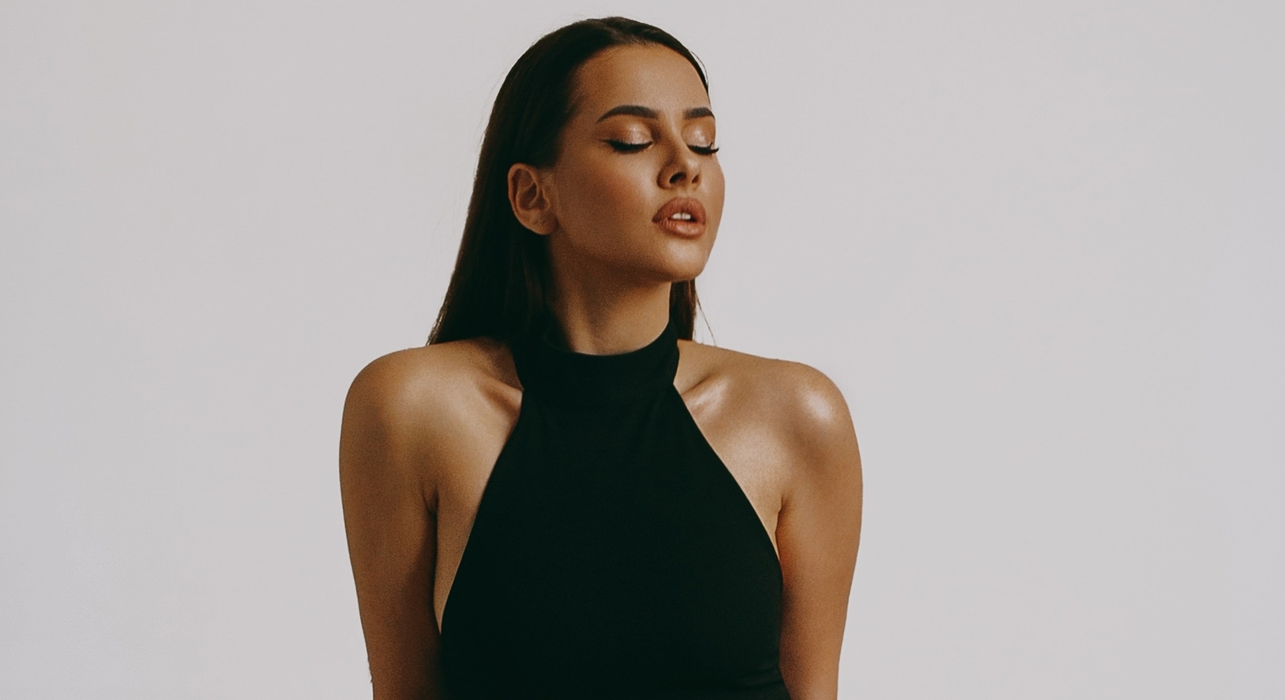 Model posing in a black halter top.