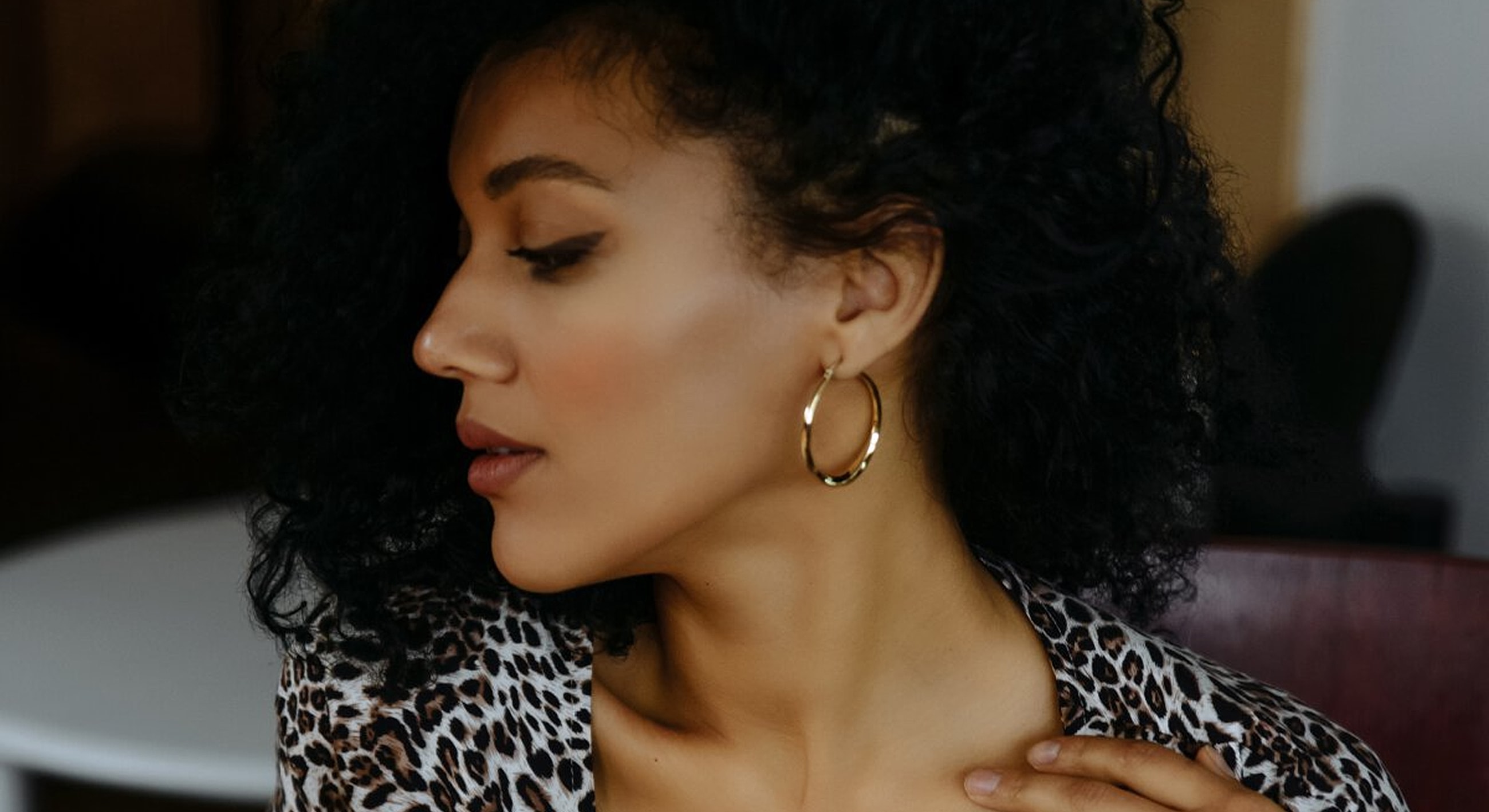 Profile of a woman with curly hair and earrings.