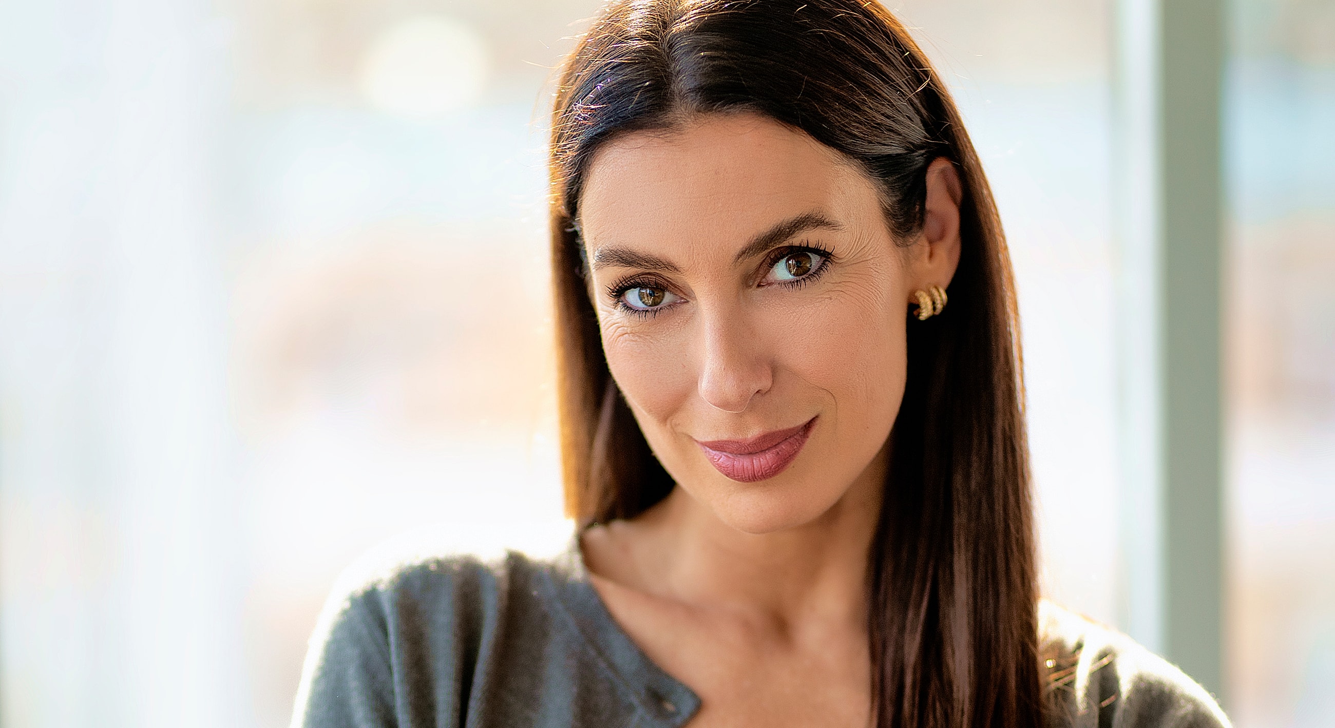 Woman smiling softly in natural light.