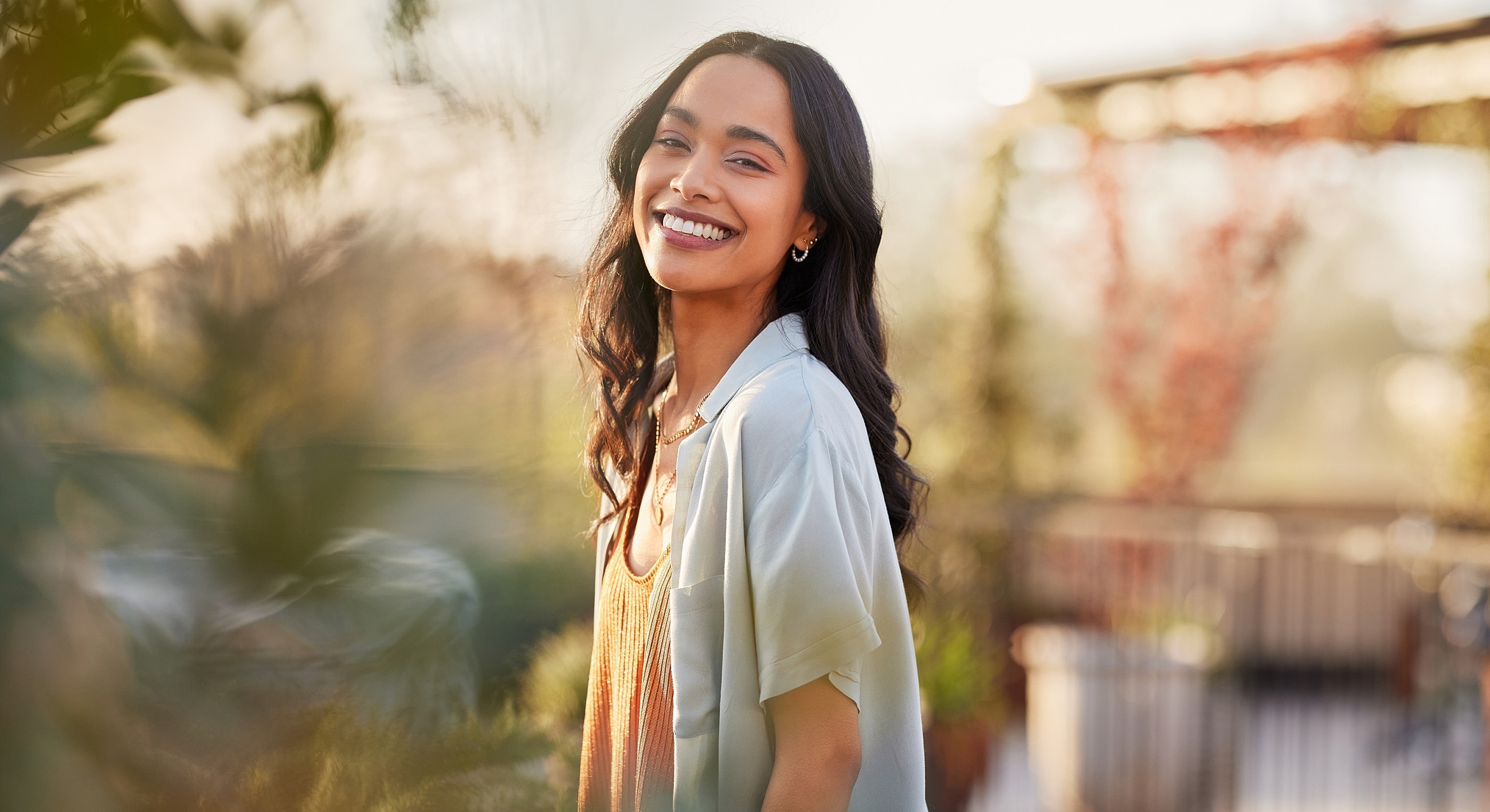 Smiling woman outdoors in soft sunlight.
