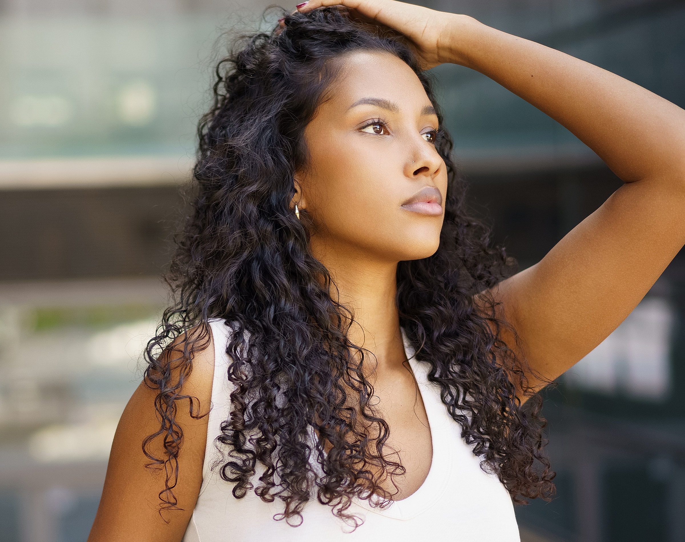 Woman with curly hair looking thoughtfully upward.