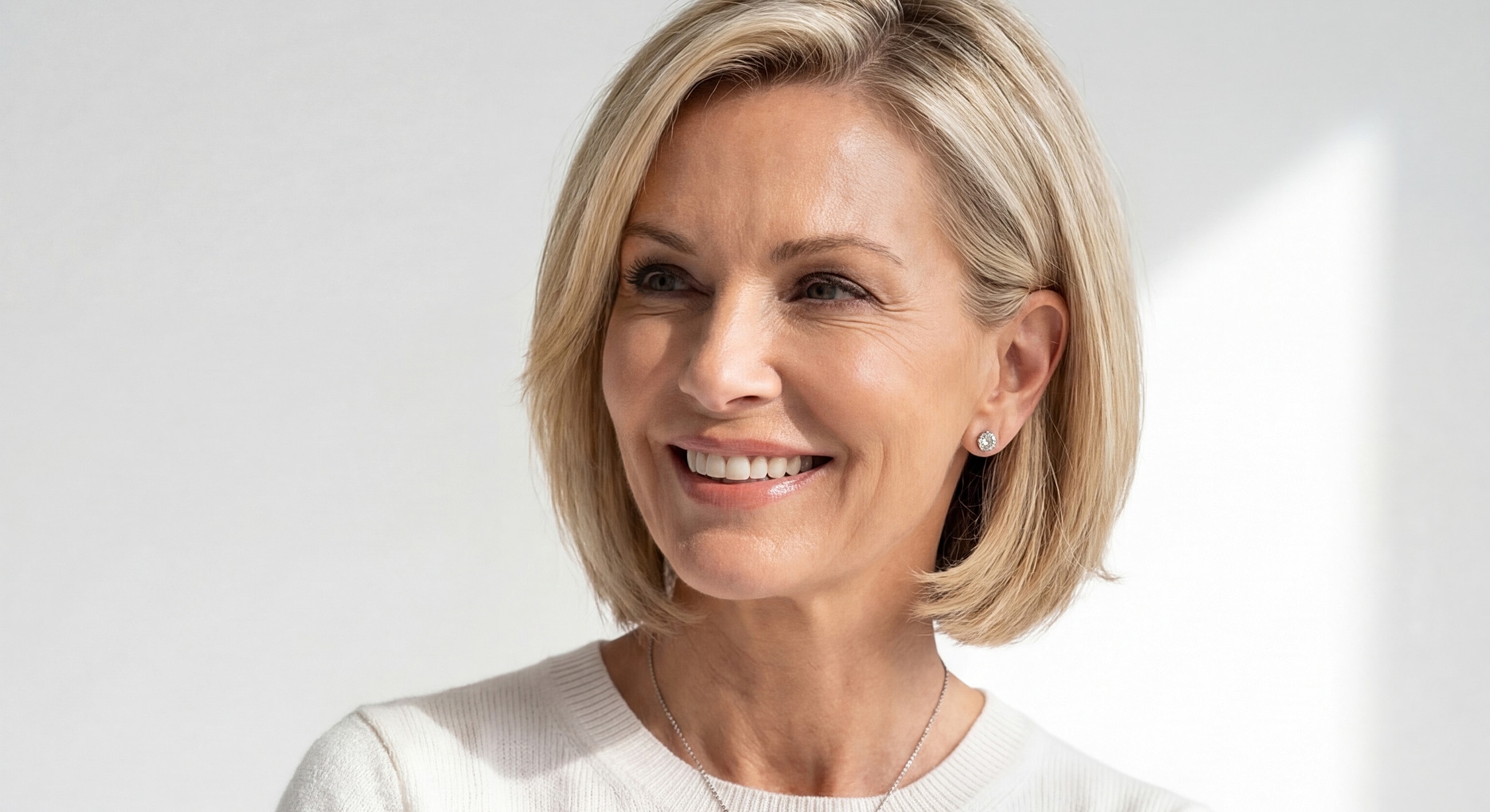 Smiling woman with blonde bob hairstyle indoors.
