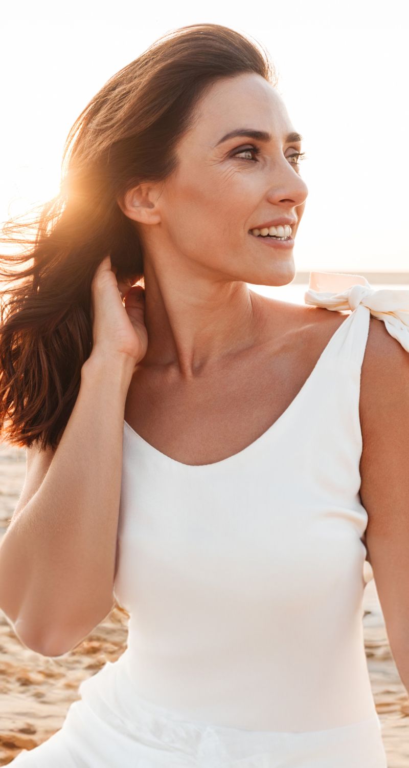 med spa patient model in white dress smiling at sunset.