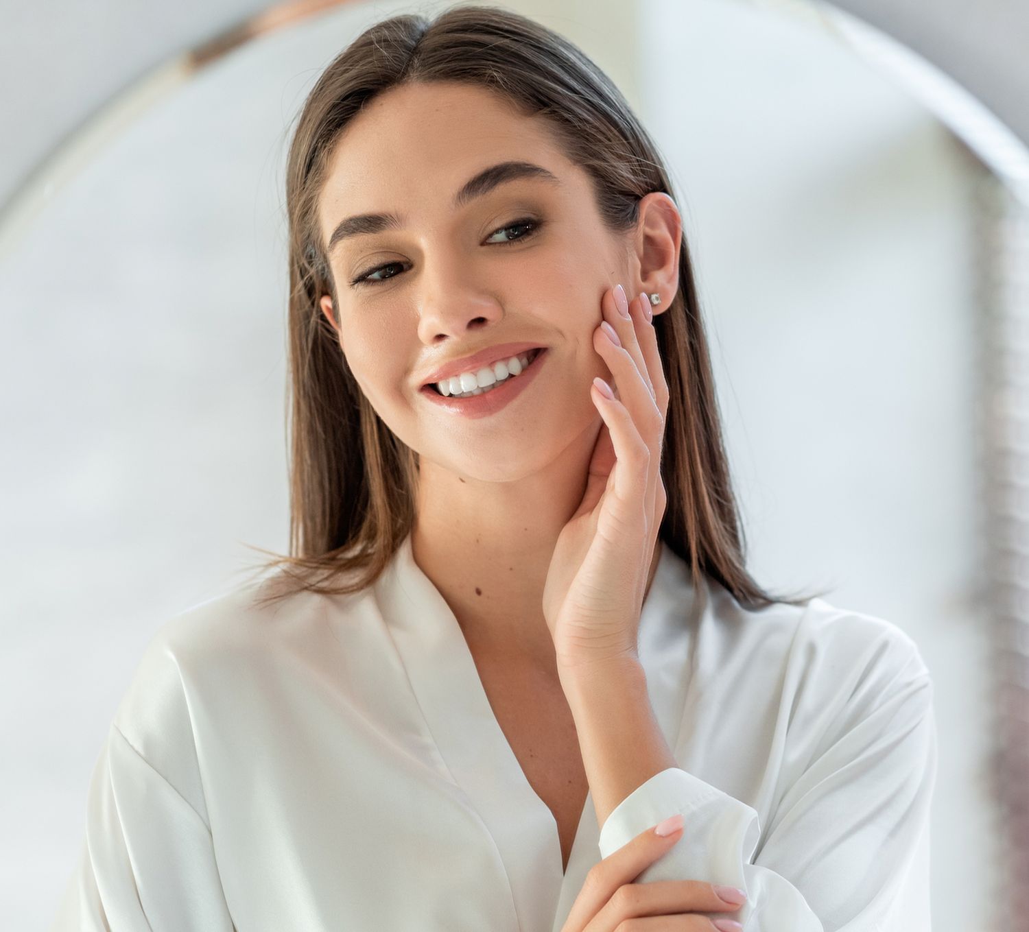 Smiling woman touching face in soft lighting.