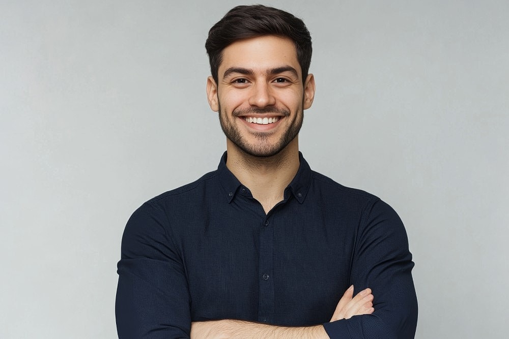 Smiling man in dark shirt representing cosmetic dermatology results.