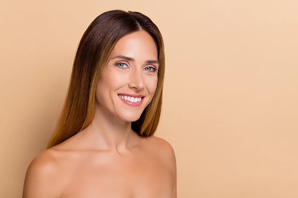 Woman with radiant skin smiling after cosmetic dermatology.