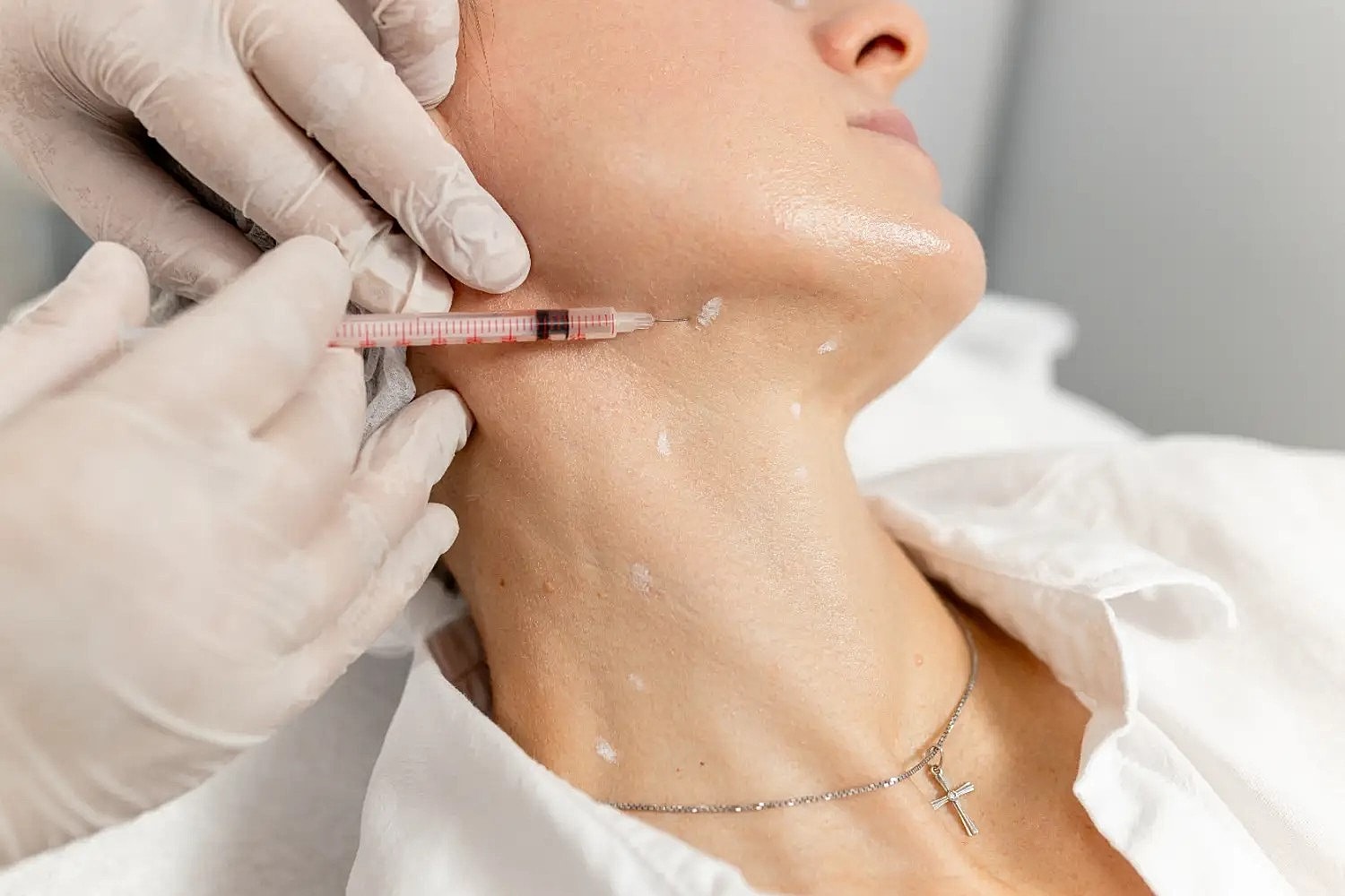 practitioner performing injectable treatment on woman’s neck area