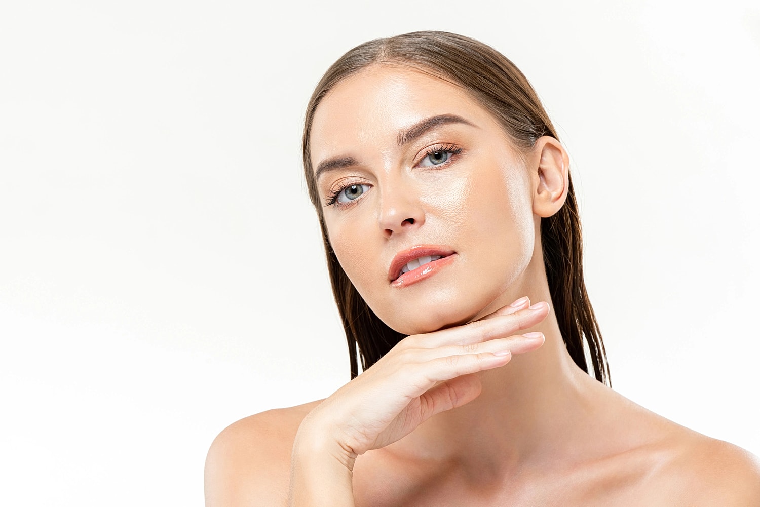 Woman with smooth-looking skin resting her chin on her hand against a light background
