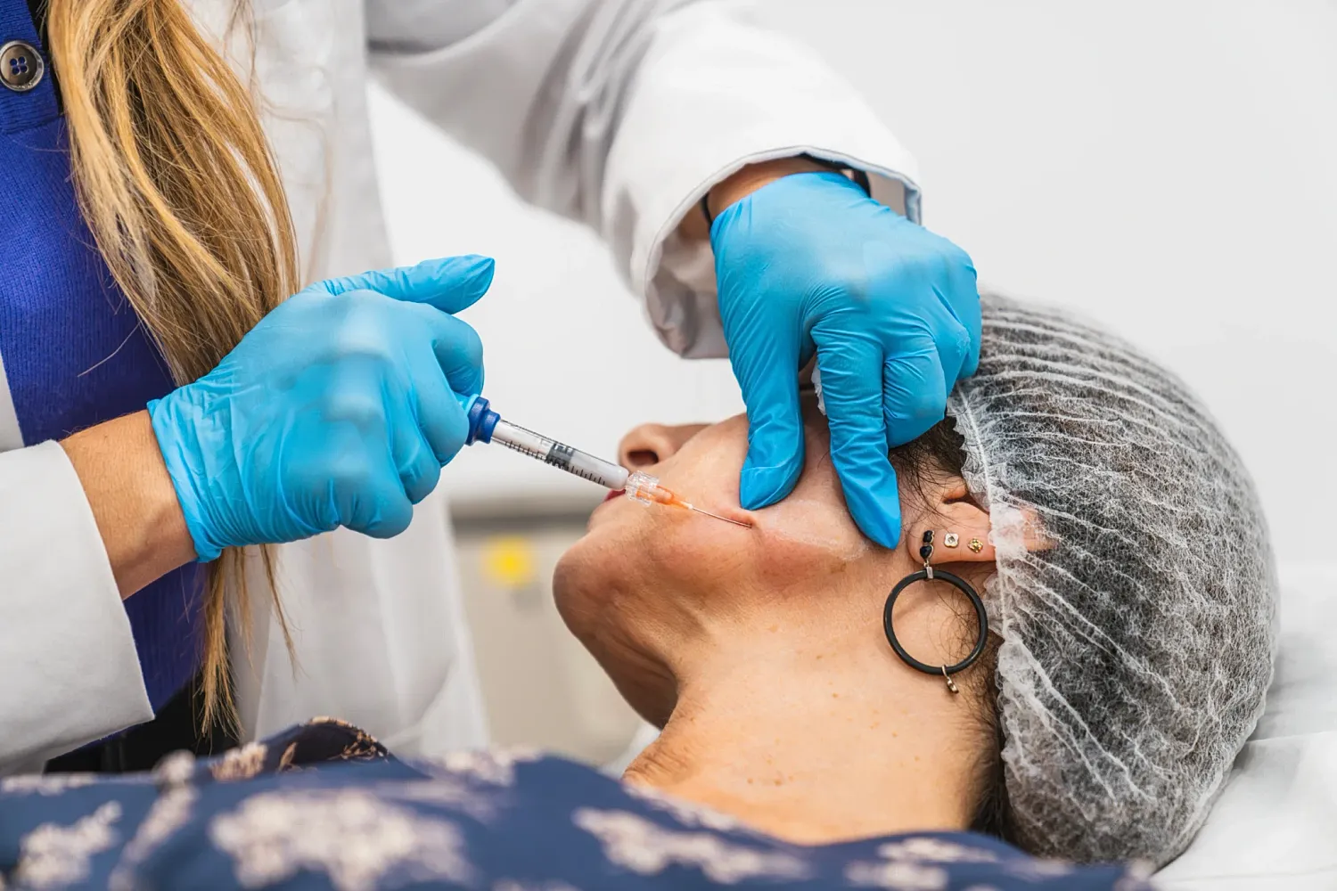 Medical professional administering injection to patient’s face.