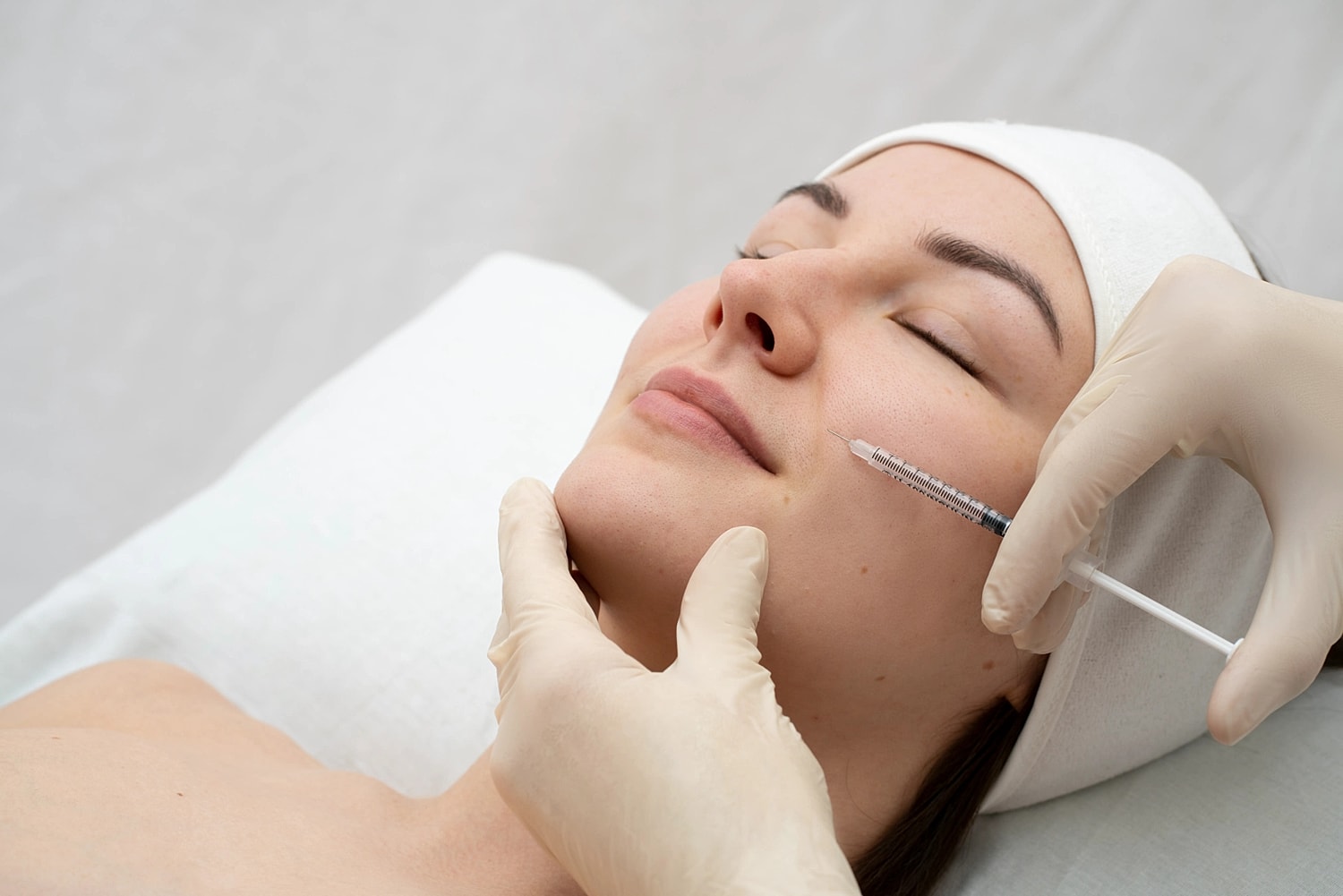 Patient receiving a facial injectable treatment while lying on a treatment bed