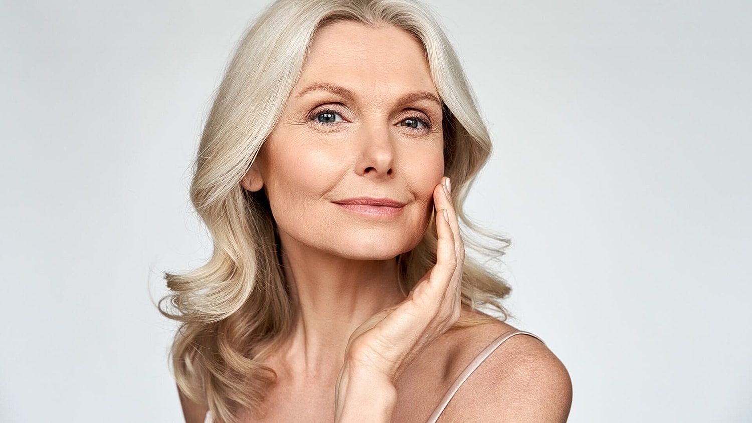 Smiling mature woman touching her face.