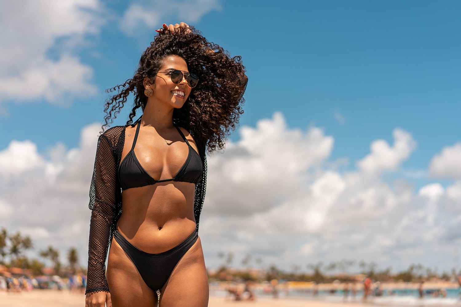 Woman in a black bikini at the beach, illustrating breast augmentation with complementary fat transfer.