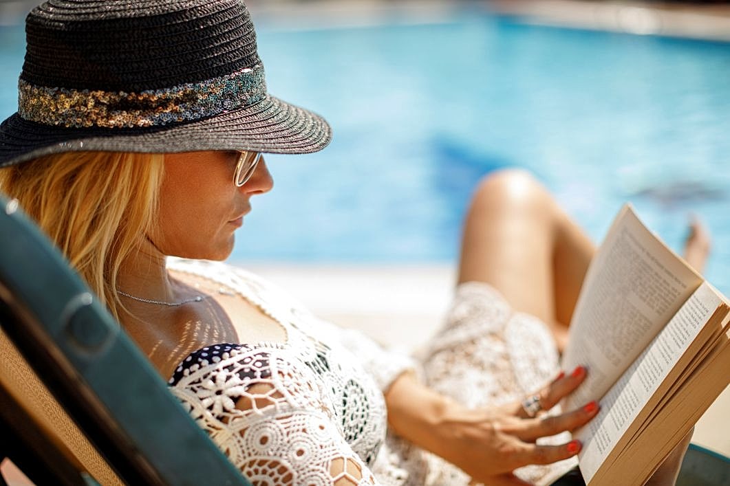 Woman relaxing by a pool, illustrating planning for Mommy Makeover surgery and recovery.