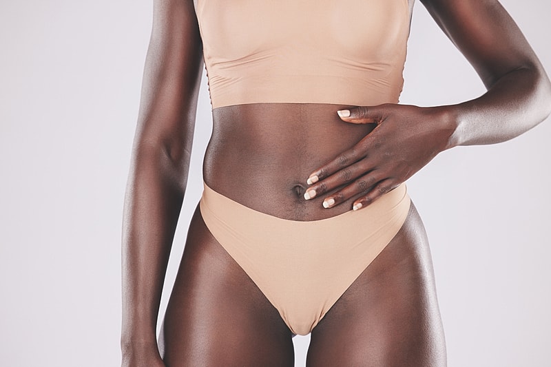 Model in nude underwear posing against a plain background.