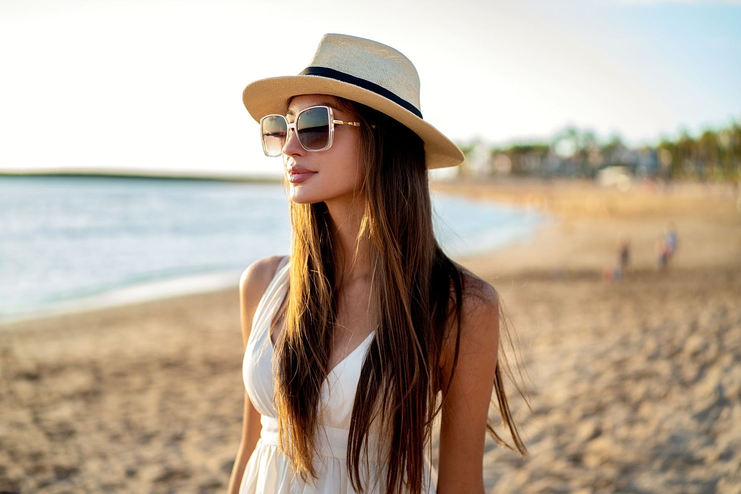 Woman enjoying a sunny beach vacation, illustrating planning ahead for liposuction results by summer.