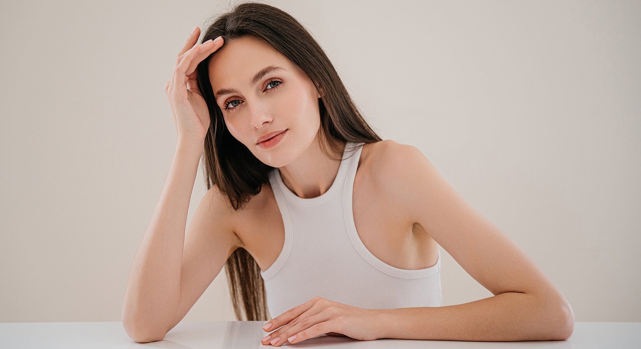 Woman with long hair posing at a table.