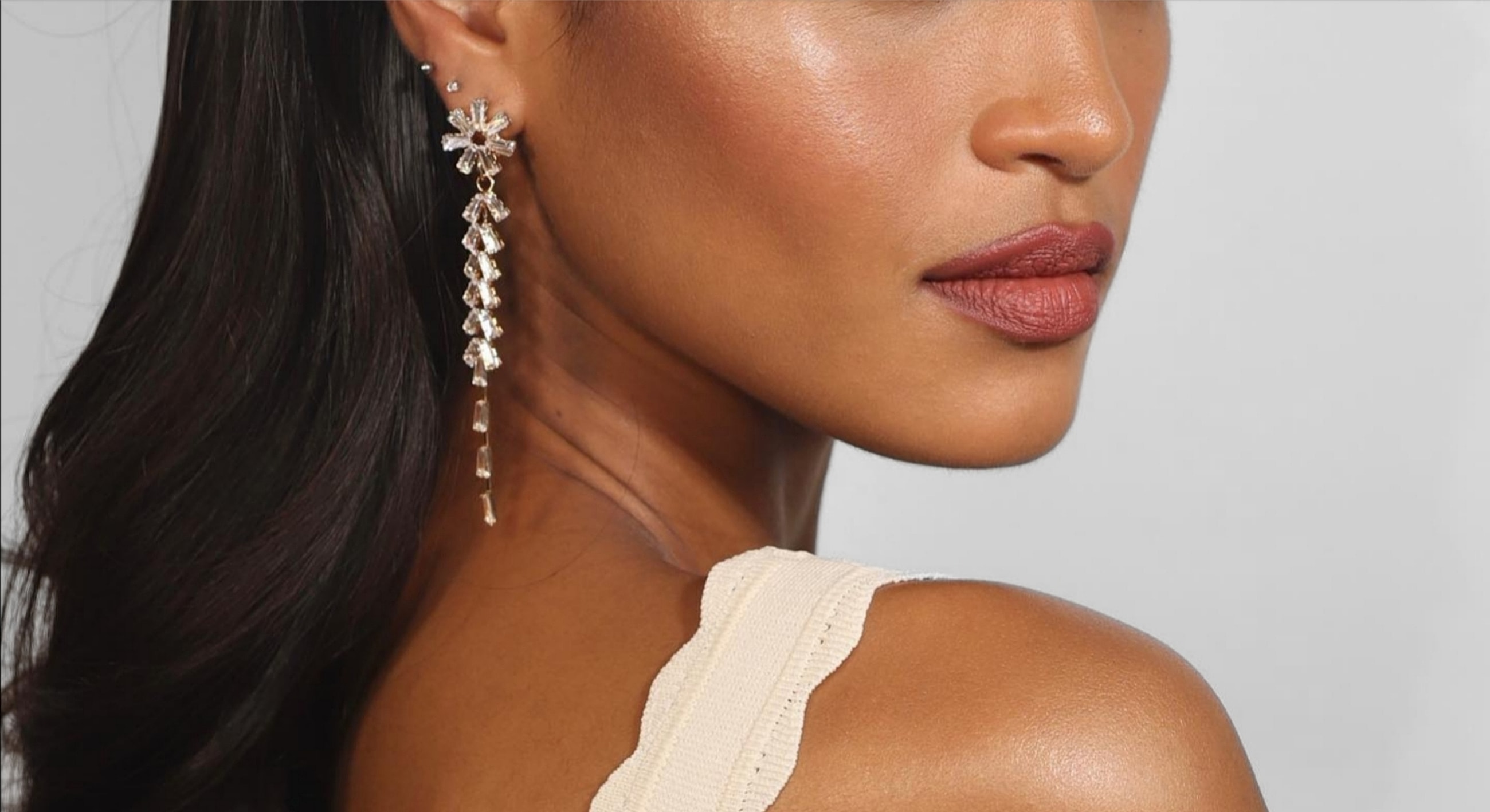 Elegant model showcasing sparkling earrings and makeup.