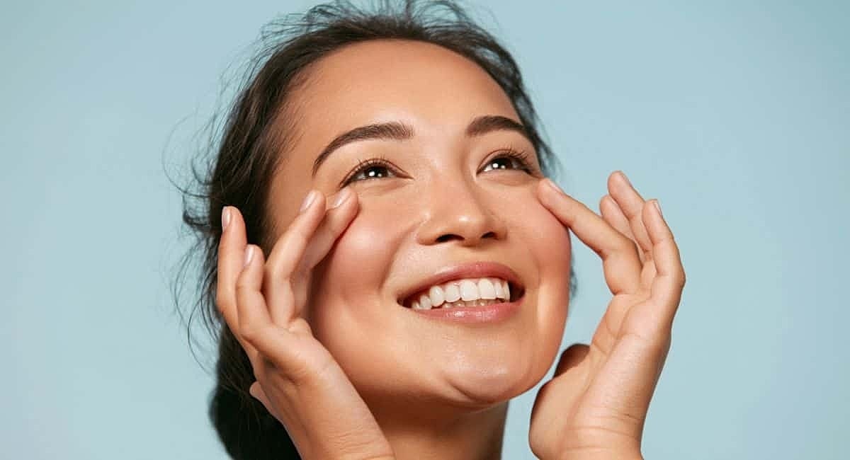 a girl is smiling while touching her cheek