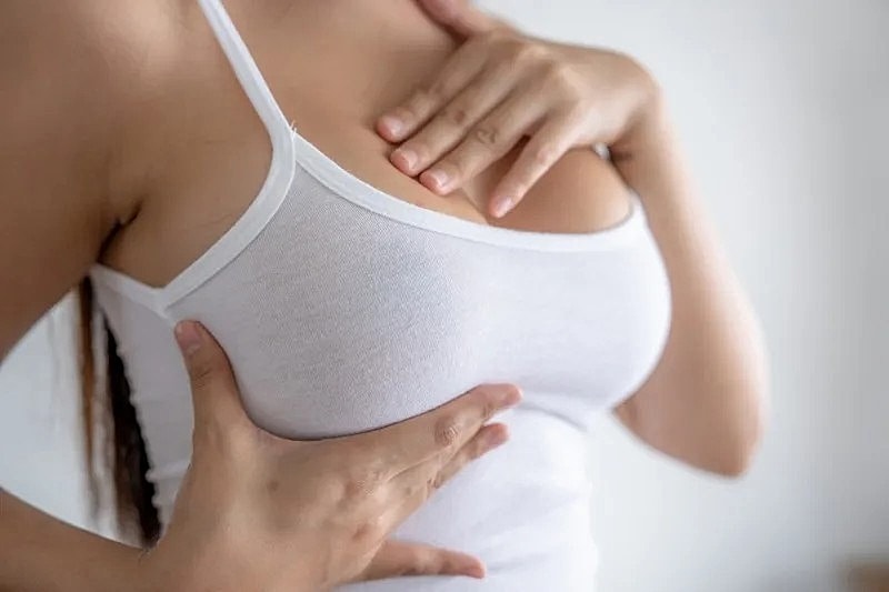 Woman adjusting her white tank top.