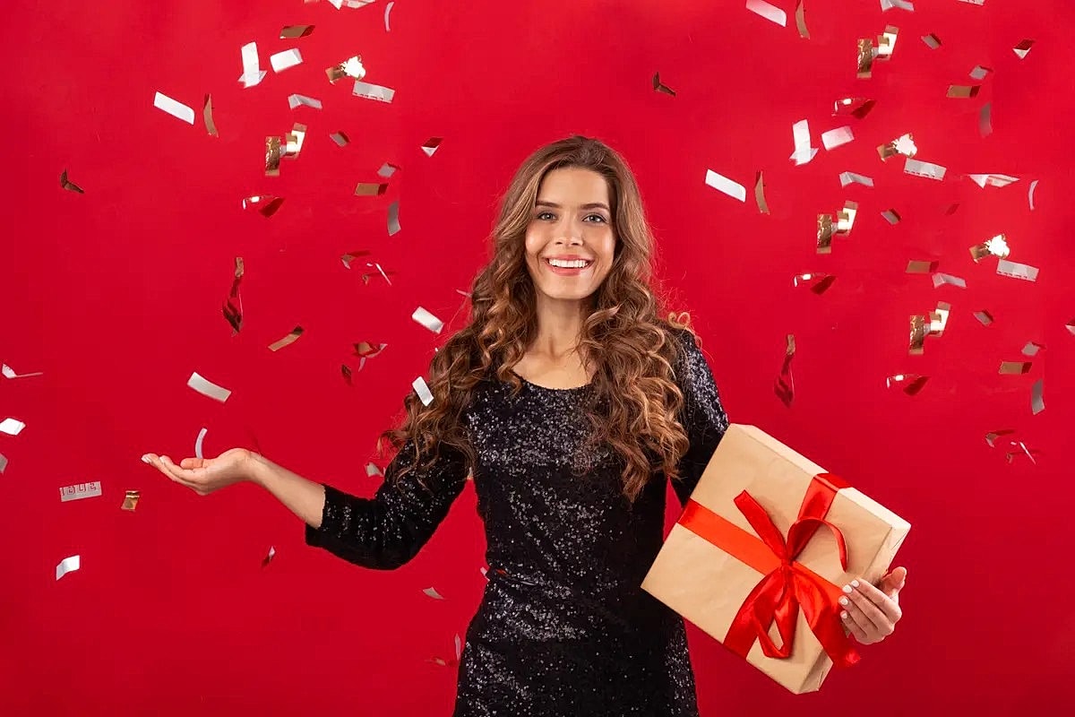 Woman celebrating with a gift and confetti.
