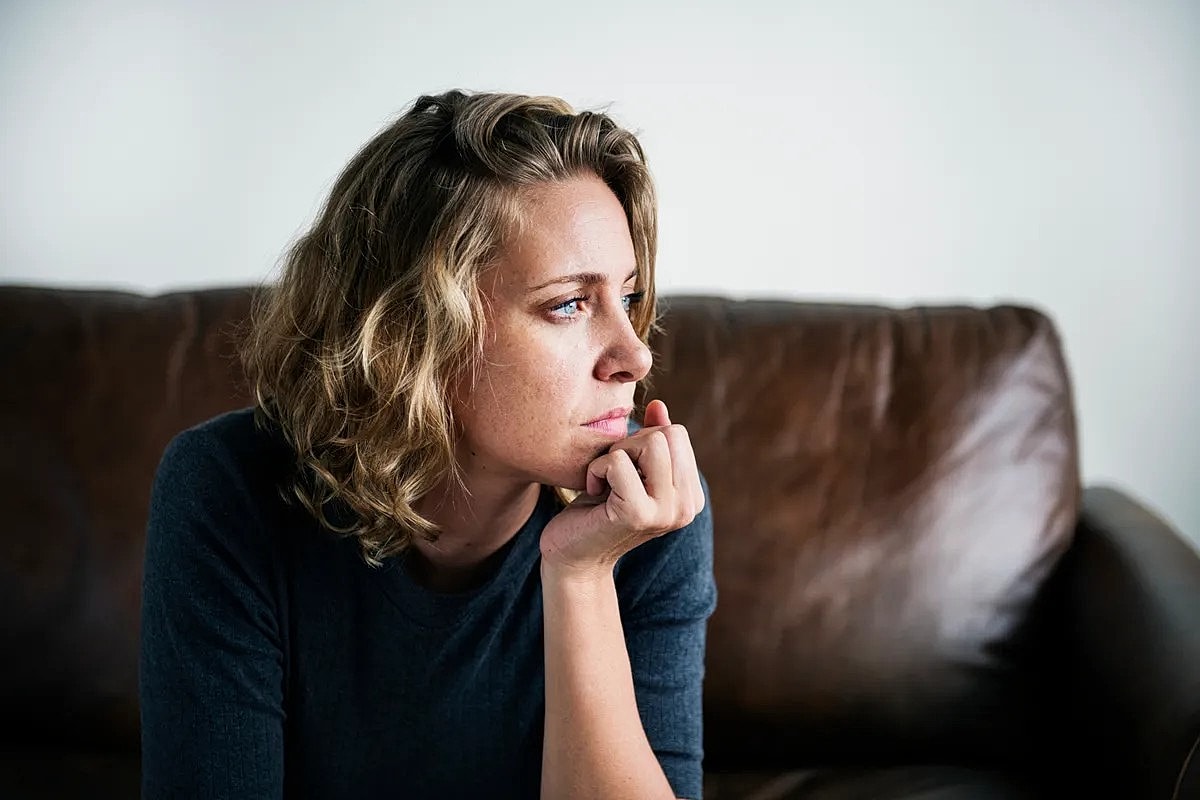 Contemplative woman resting chin on hand.