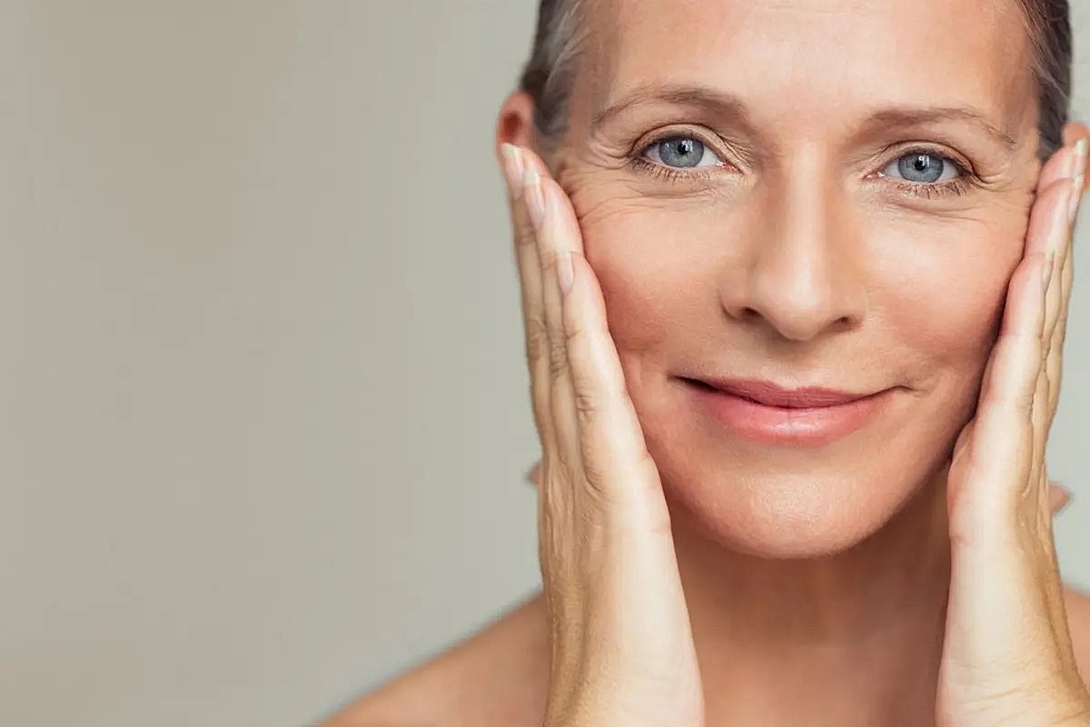 Smiling woman touching her face gently.