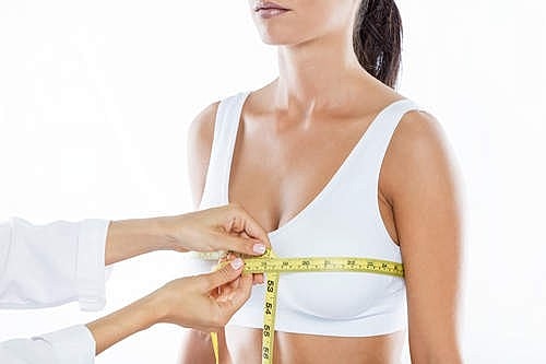 Measuring woman's bust with tape measure.