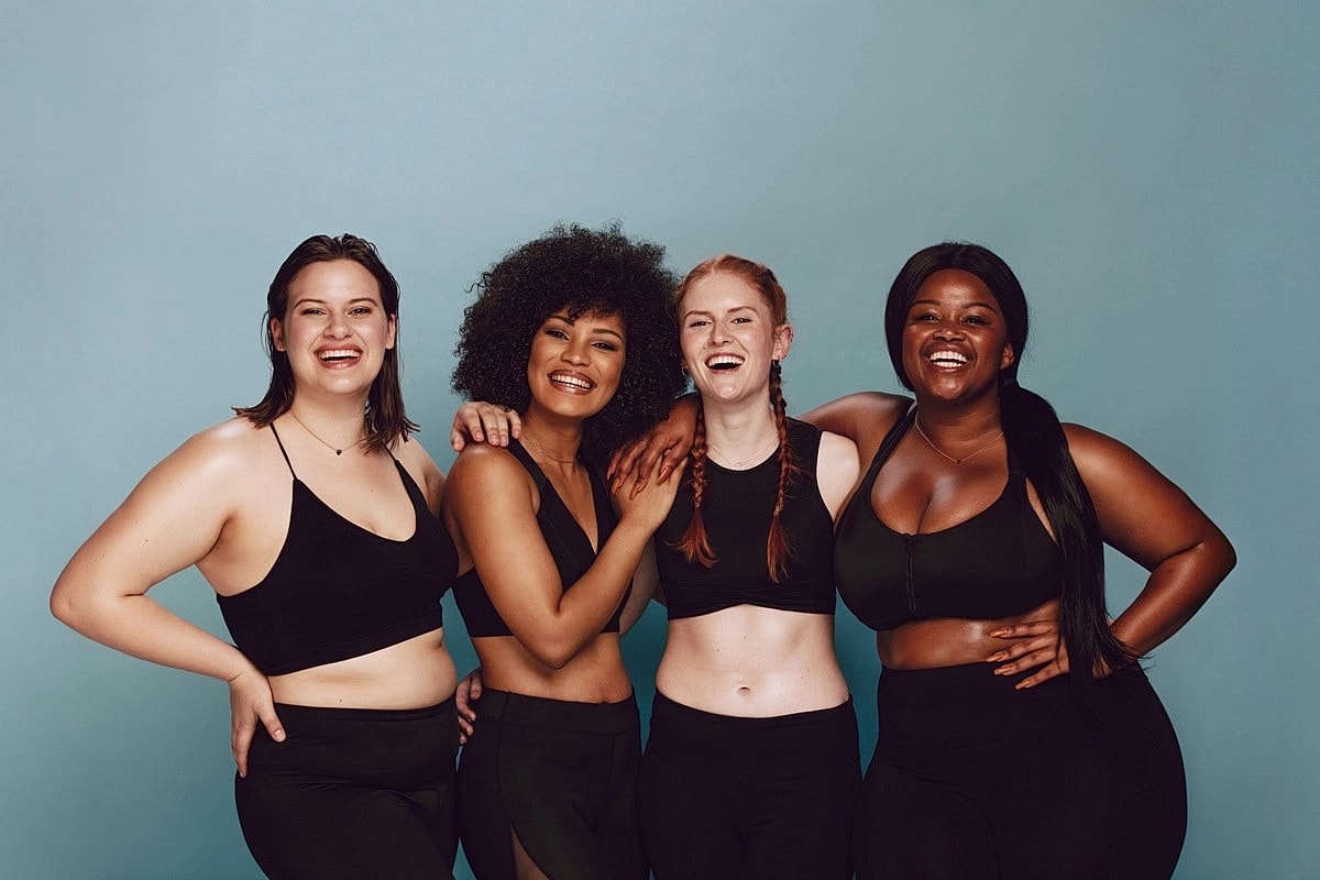 Four diverse women smiling and posing together.