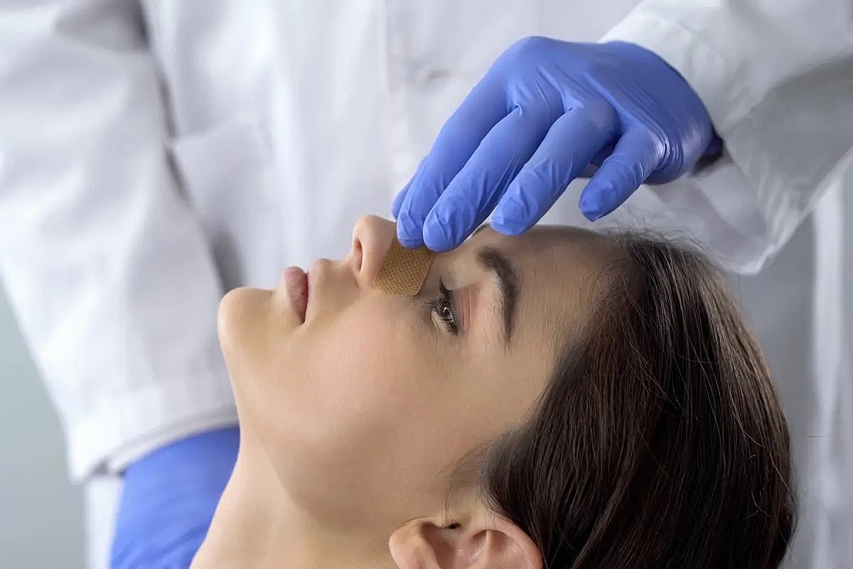 Applying a bandage to a patient's nose.