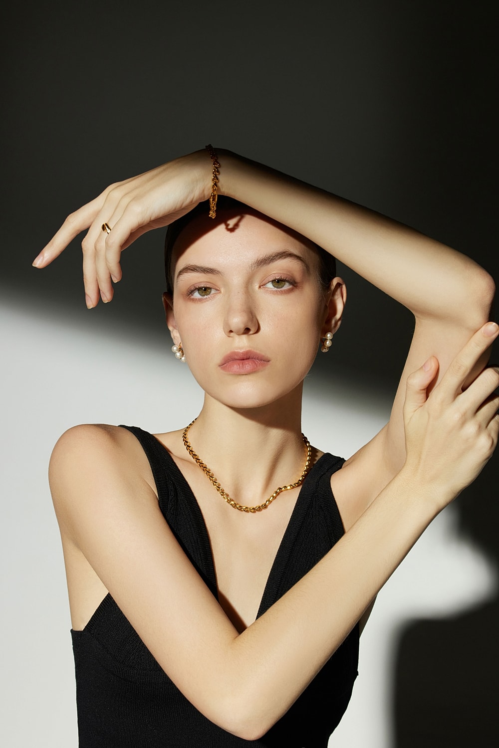 Model wearing jewelry in dramatic lighting.