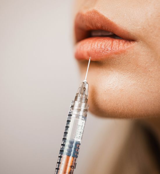 Lip injection procedure with syringe and lips.