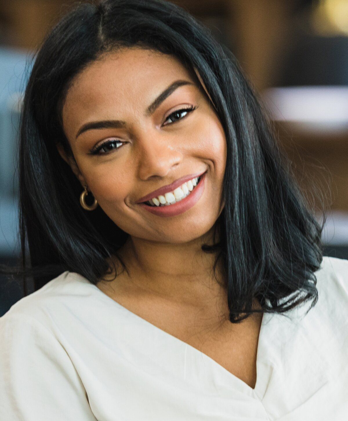 Smiling woman with long black hair and earrings.