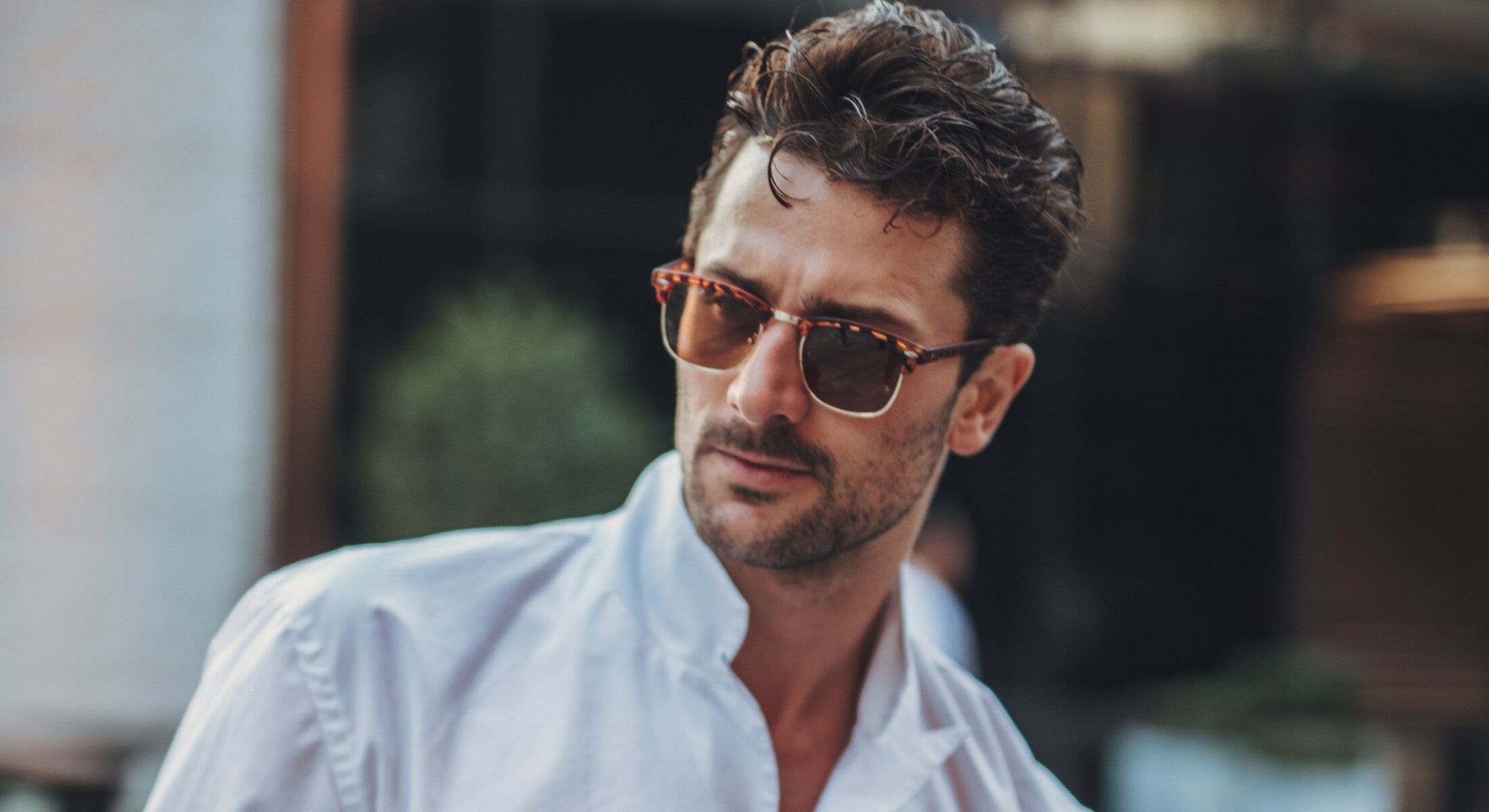 Man wearing sunglasses and a white shirt.