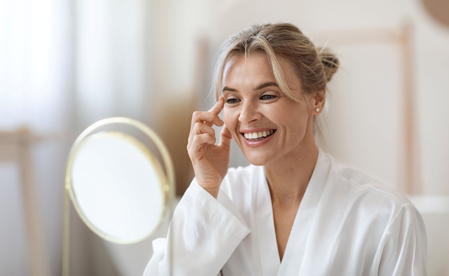Smiling woman touching the skin near her eye in natural light, symbolizing refreshed, youthful results from facial rejuvenation treatments in Houston with Dr. Paul Fortes.