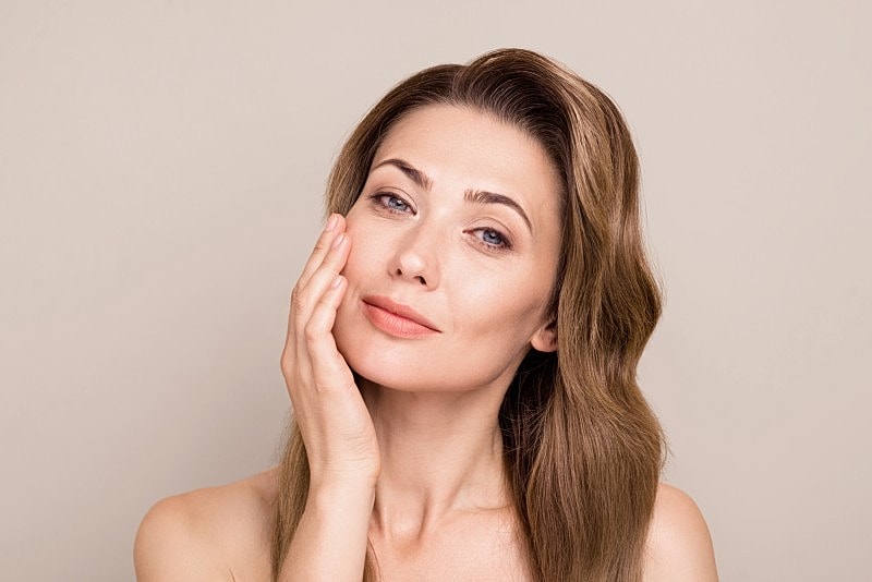 Woman gently touching her face, soft expression.