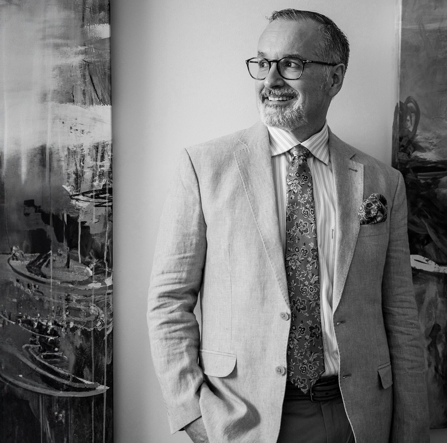 Man in suit smiling by abstract artwork.