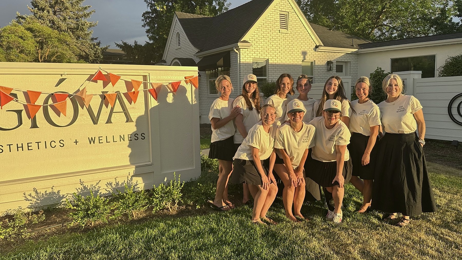 A group gathered beside the Gióva sign and orange bunting at The Gióva Market.