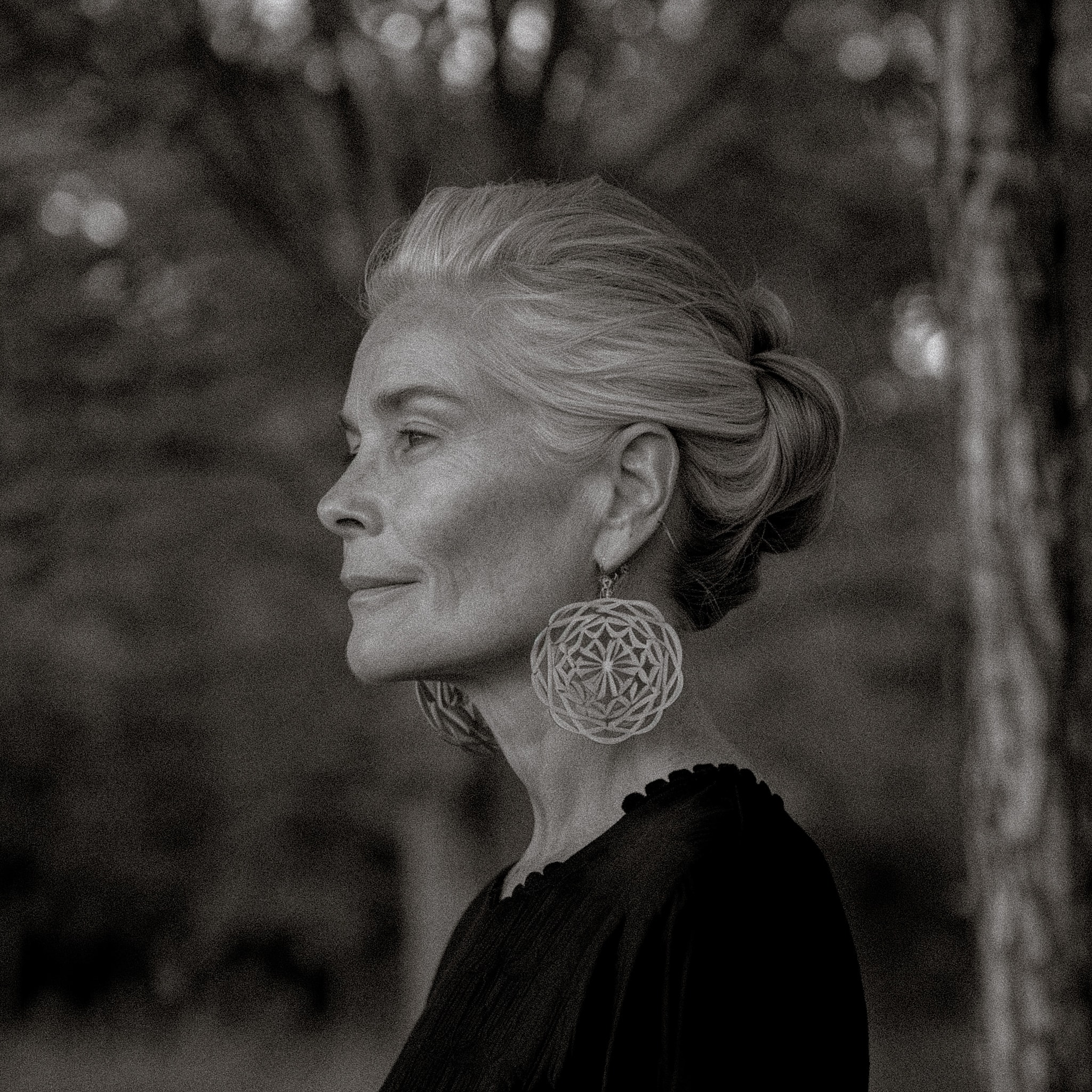 Black-and-white profile of a silver-haired woman with natural neck texture and statement earrings